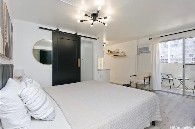 bedroom featuring a barn door, a wall unit AC, and light wood finished floors