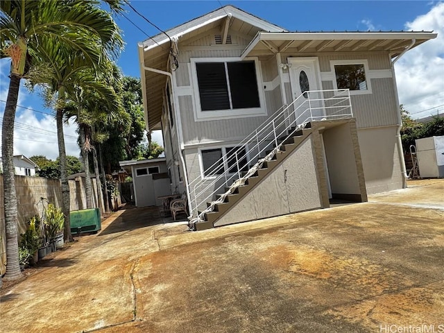 view of front facade with stairs, a patio, and fence