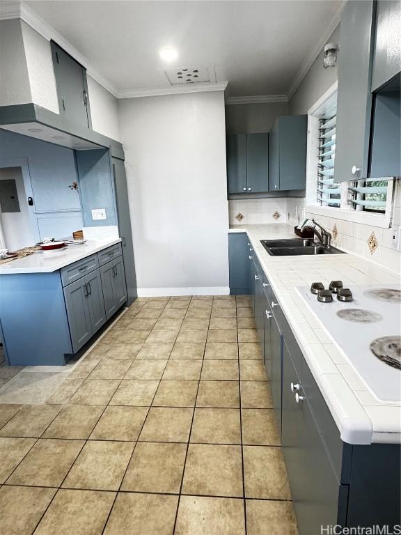 kitchen featuring backsplash, light tile patterned floors, ornamental molding, and a sink