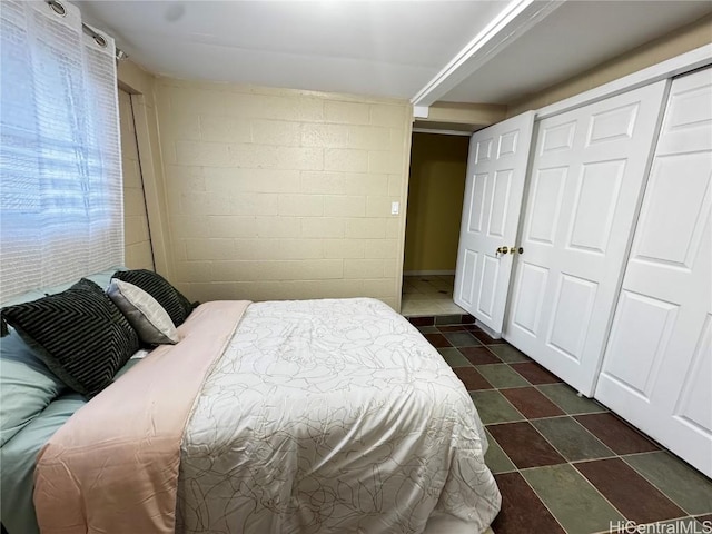 bedroom featuring concrete block wall and a closet