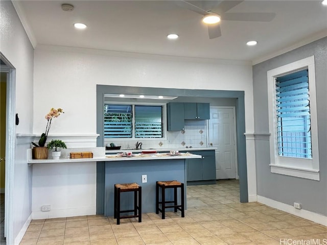 kitchen featuring a kitchen breakfast bar, backsplash, a peninsula, crown molding, and ceiling fan