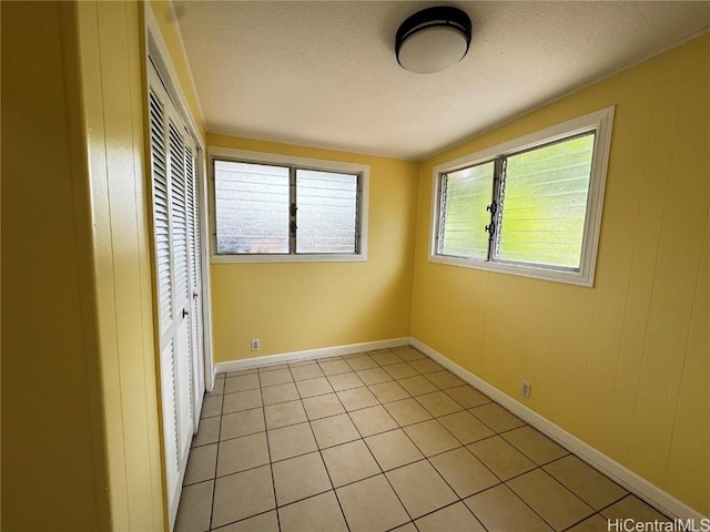 unfurnished bedroom with light tile patterned floors, baseboards, a closet, and a textured ceiling