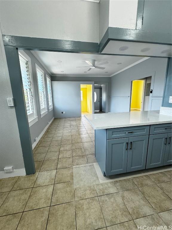 kitchen with light tile patterned floors, gray cabinets, ceiling fan, ornamental molding, and light countertops