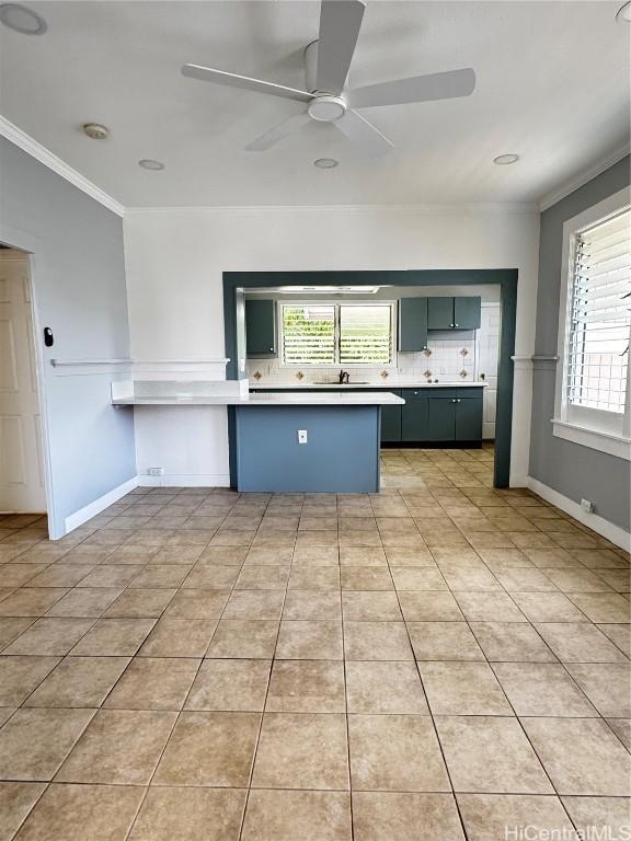 kitchen featuring ornamental molding, a ceiling fan, backsplash, a peninsula, and light tile patterned flooring