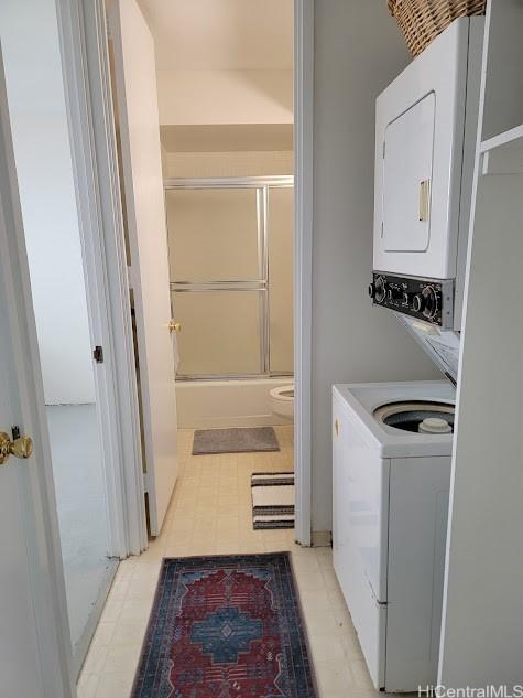 clothes washing area with stacked washer / drying machine, laundry area, and light floors