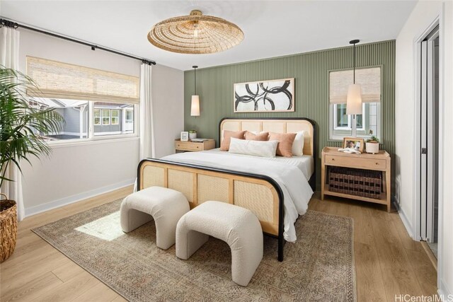 bedroom featuring an accent wall, wood finished floors, and baseboards