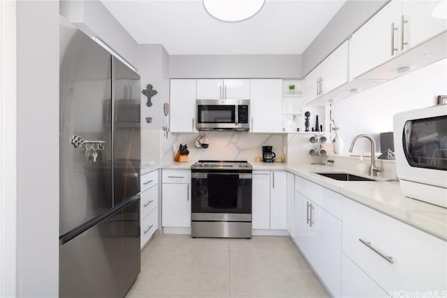 kitchen with a sink, open shelves, appliances with stainless steel finishes, light countertops, and light tile patterned floors