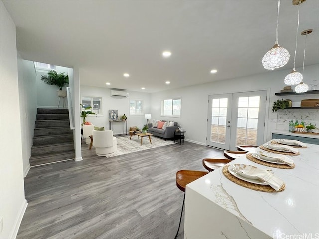 living area featuring recessed lighting, wood finished floors, a wall unit AC, baseboards, and stairs