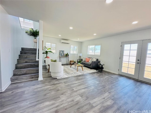 living room with an AC wall unit, wood finished floors, recessed lighting, and stairway