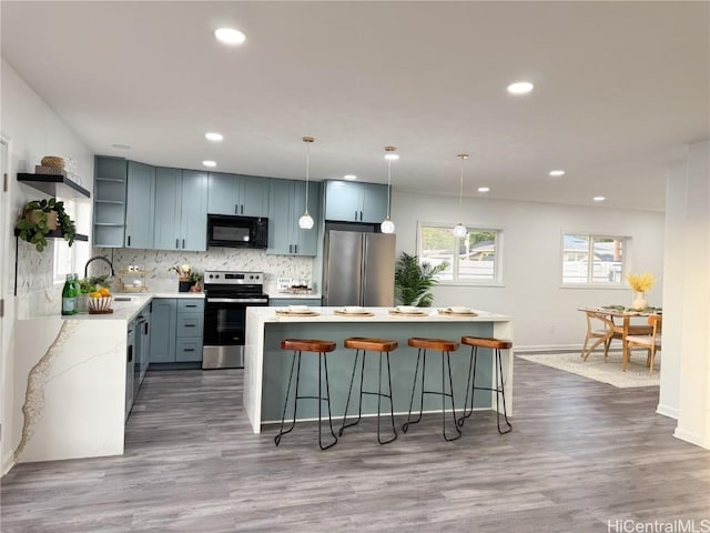 kitchen featuring open shelves, a center island, tasteful backsplash, appliances with stainless steel finishes, and a breakfast bar area