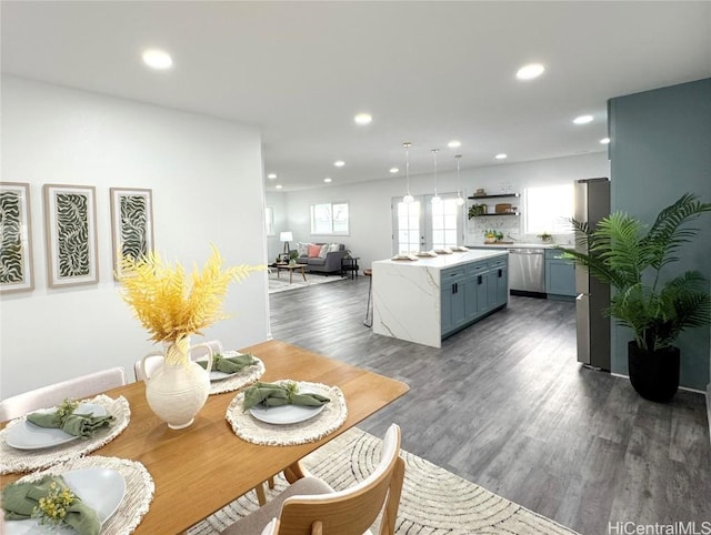 kitchen featuring recessed lighting, light countertops, stainless steel dishwasher, a kitchen island, and dark wood-style flooring