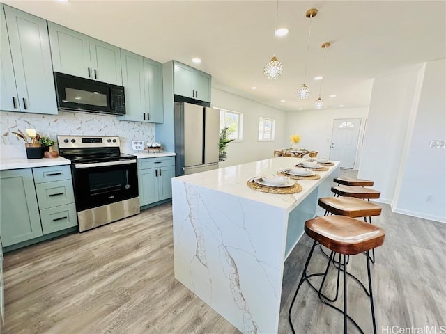 kitchen featuring black microwave, light wood finished floors, stainless steel electric range, and freestanding refrigerator