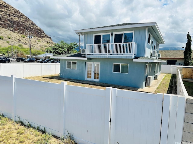 back of property with french doors, a fenced backyard, a balcony, and a mountain view