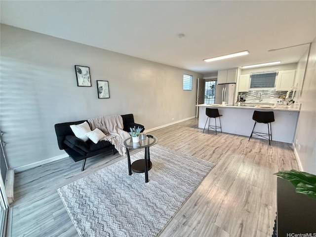 living area with light wood-style flooring and baseboards