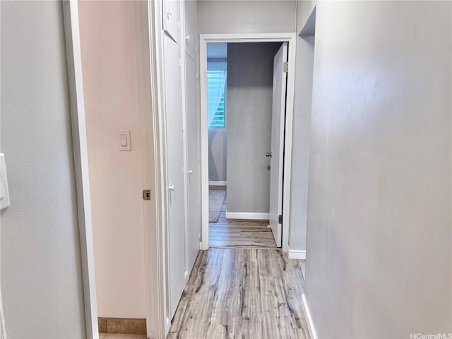 corridor with light wood-style floors and baseboards