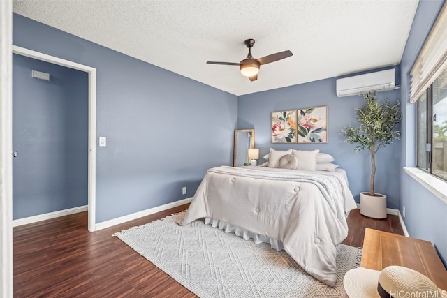bedroom featuring baseboards, a textured ceiling, a ceiling fan, a wall mounted air conditioner, and wood finished floors