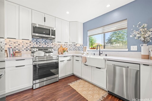 kitchen featuring a sink, backsplash, white cabinetry, appliances with stainless steel finishes, and dark wood-type flooring