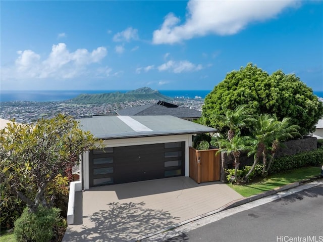 contemporary house with driveway, an attached garage, and a water view
