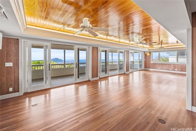 unfurnished living room with a ceiling fan, plenty of natural light, wooden ceiling, and a tray ceiling