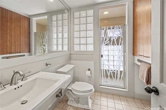 bathroom with a wealth of natural light, toilet, tile patterned flooring, and a sink