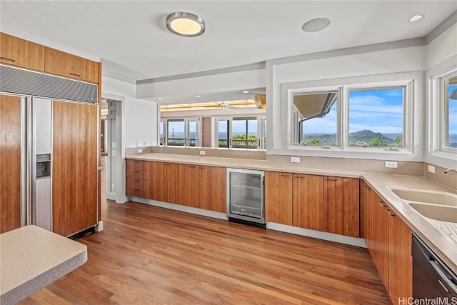 kitchen featuring paneled built in refrigerator, light wood-style flooring, wine cooler, dishwashing machine, and brown cabinetry