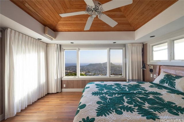 bedroom featuring a tray ceiling, light wood finished floors, wooden ceiling, and a mountain view