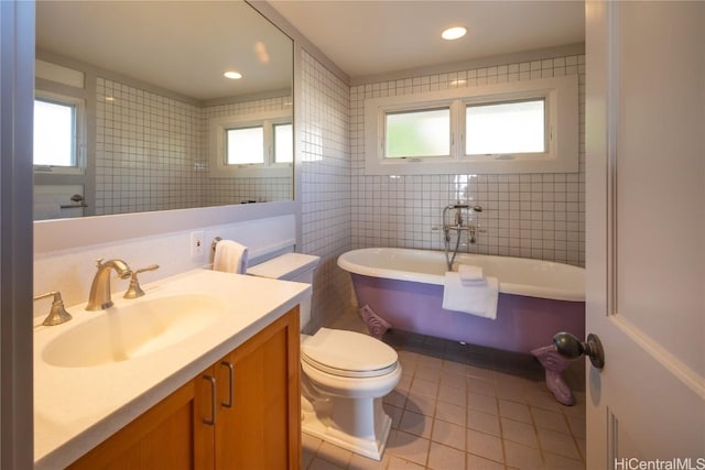 bathroom featuring plenty of natural light, toilet, a freestanding tub, tile patterned floors, and vanity