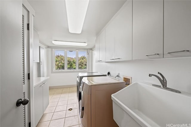 laundry room featuring a sink, baseboards, light tile patterned floors, independent washer and dryer, and cabinet space