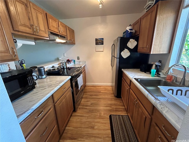 94-203 Paioa Pl Unit P201, Waipahu, HI 96797 - kitchen with stainless steel electric range, black microwave, under cabinet range hood, light wood-style floors, and brown cabinetry