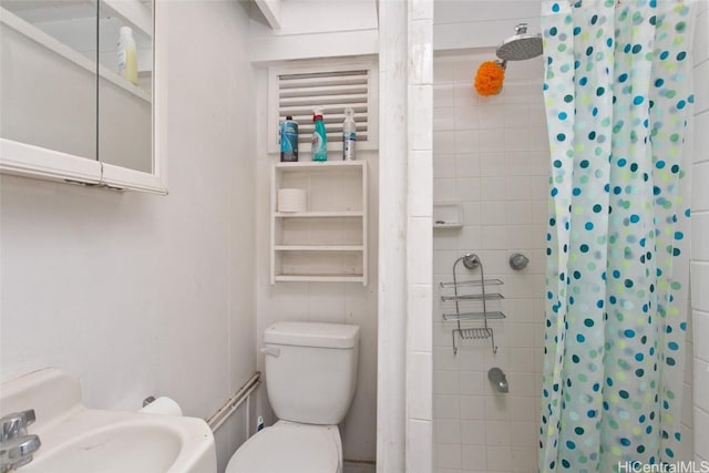 full bath with a tile shower, toilet, and a sink