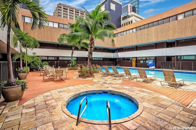 pool featuring a hot tub and fence