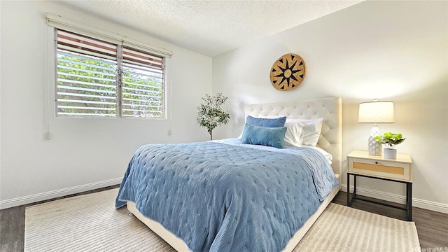 bedroom featuring baseboards, a textured ceiling, and wood finished floors