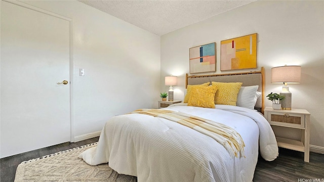 bedroom featuring baseboards, wood finished floors, and a textured ceiling