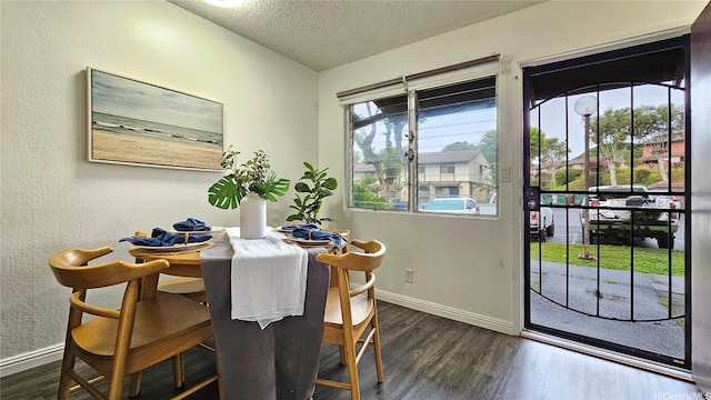dining area with dark wood-type flooring, a textured ceiling, and baseboards