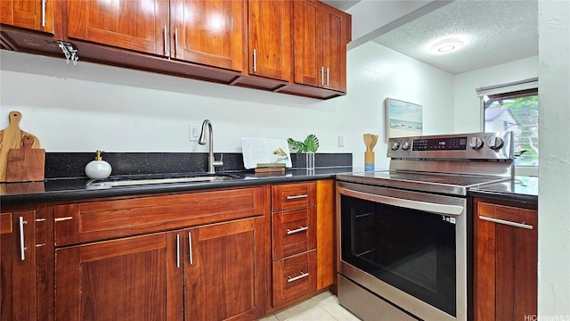 kitchen featuring brown cabinetry, a textured ceiling, stainless steel electric range oven, and dark countertops