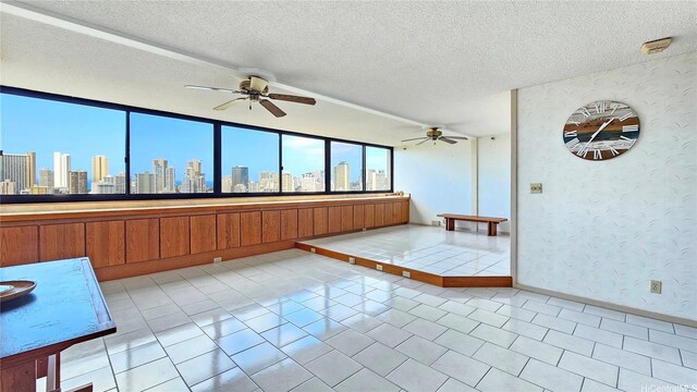 unfurnished room featuring baseboards, a ceiling fan, wallpapered walls, and a city view