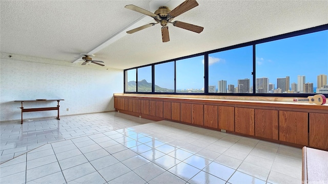 interior space featuring a view of city, a textured ceiling, ceiling fan, and light tile patterned floors