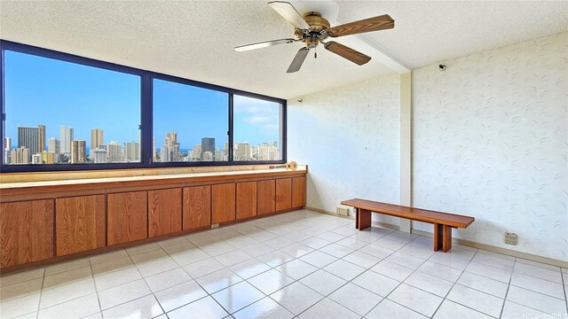 unfurnished room featuring ceiling fan, a city view, and a textured ceiling