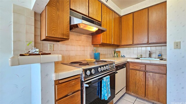 kitchen with white dishwasher, tile counters, electric range oven, under cabinet range hood, and a sink