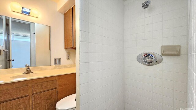 bathroom featuring vanity, a tile shower, and toilet