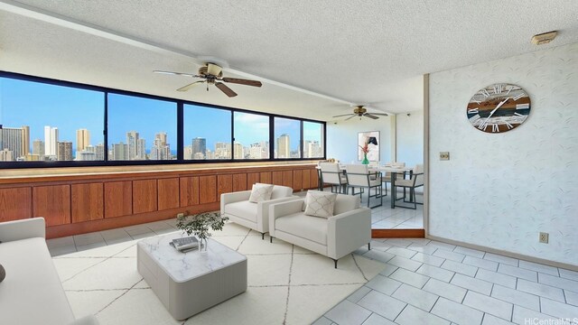 living area featuring a view of city, ceiling fan, wallpapered walls, and baseboards