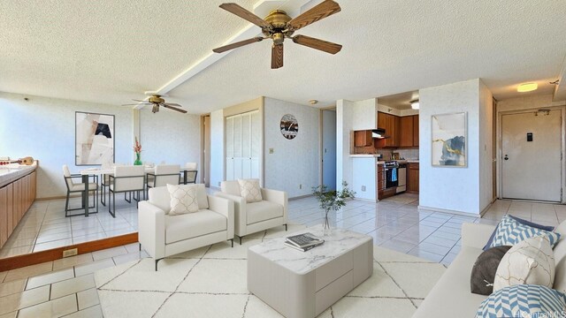 living room featuring light tile patterned floors, baseboards, a ceiling fan, and a textured ceiling