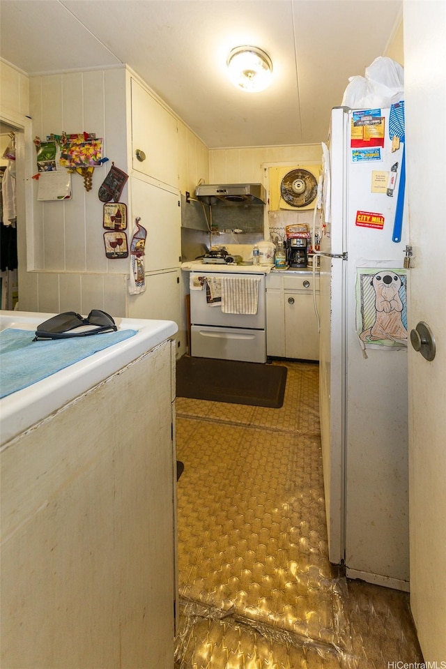 kitchen featuring under cabinet range hood, light countertops, white appliances, and tile patterned floors