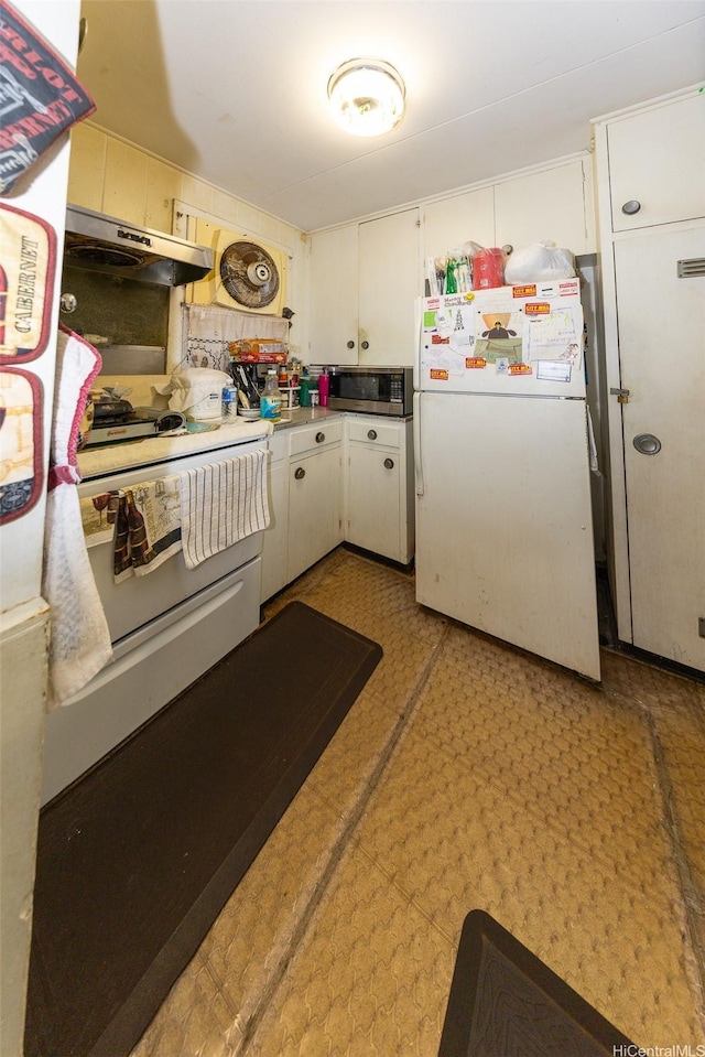 kitchen with light floors, white cabinetry, stainless steel microwave, under cabinet range hood, and freestanding refrigerator