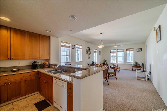 kitchen featuring recessed lighting, a peninsula, brown cabinets, dishwasher, and a sink