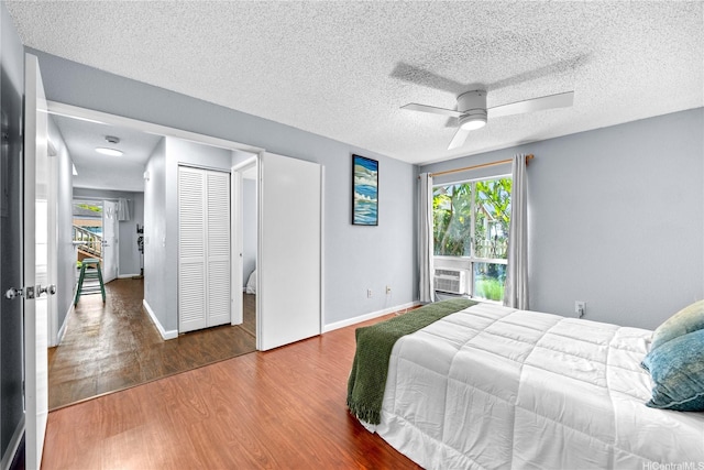 bedroom featuring multiple windows, wood finished floors, a textured ceiling, baseboards, and ceiling fan