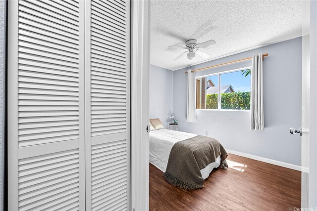 bedroom featuring wood finished floors, baseboards, a textured ceiling, and a closet