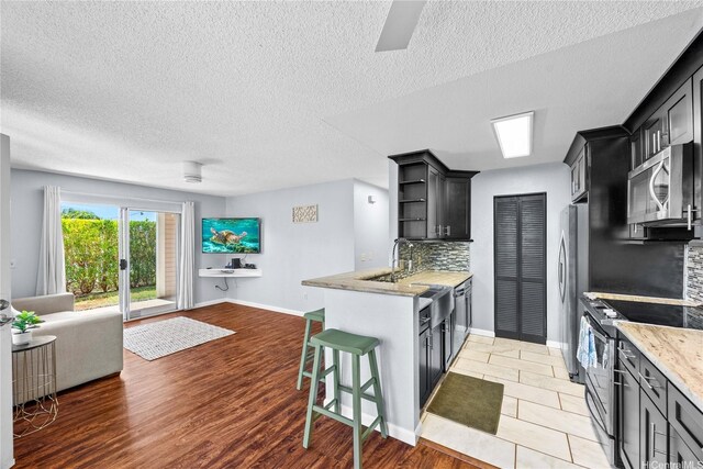 kitchen with appliances with stainless steel finishes, open floor plan, decorative backsplash, open shelves, and baseboards