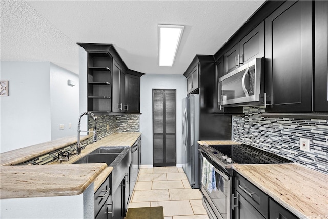 kitchen featuring stainless steel appliances, open shelves, a sink, a peninsula, and decorative backsplash