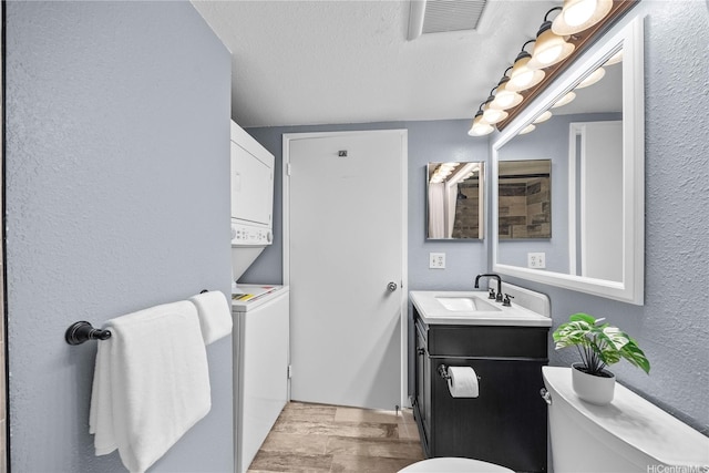 bathroom featuring a textured wall, wood finished floors, toilet, and vanity